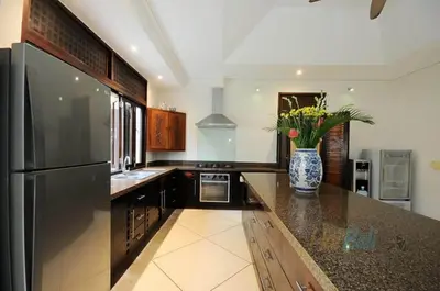 a kitchen with a refrigerator and a vase with flowers at Villa Seminyak William in Seminyak
