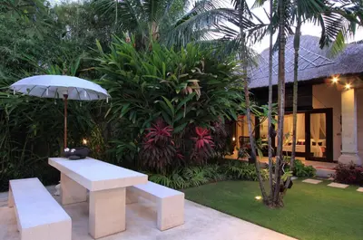 a bench and an umbrella in front of a house at Villa Maju in Seminyak