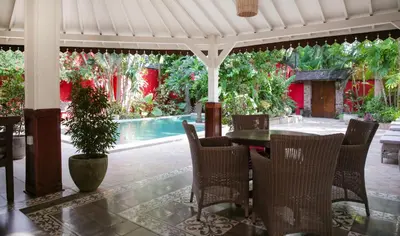 a patio with a table and chairs and a pool at Villa Hangat in Seminyak