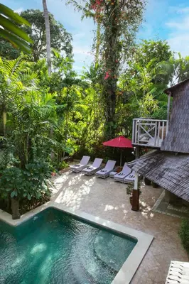 a swimming pool with lounge chairs and an umbrella at Villa Hangat in Seminyak