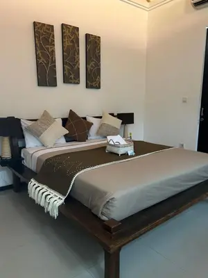 a large bed in a room with several pillows at Artemis Villa Hotel in Seminyak