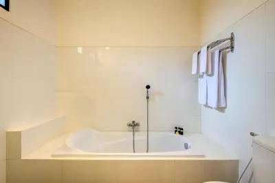 a white bath tub in a white bathroom at Gracia Bali Villas & Apartment Managed by Manara in Seminyak