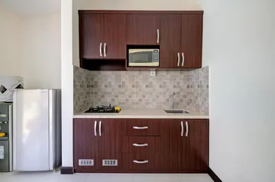 a kitchen with wooden cabinets and a microwave at Gracia Bali Villas & Apartment Managed by Manara in Seminyak