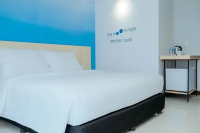 a white bed in a room with a table at Bloo Bali Hotel in Legian