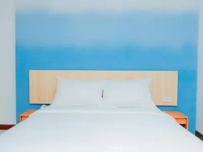 a large white bed with a blue wall at Bloo Bali Hotel in Legian