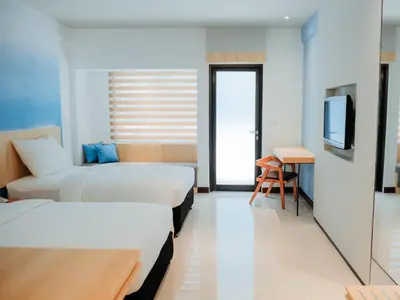 a hotel room with two beds and a television at Bloo Bali Hotel in Legian