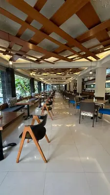 a lobby with chairs and tables and people sitting on them at Bloo Bali Hotel in Legian