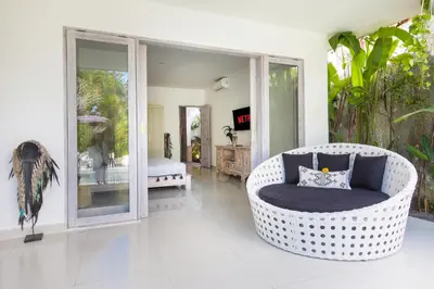 a living room with a wicker chair and a bedroom at Villa Maviba in Seminyak