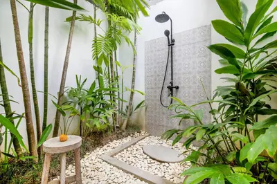 a shower in a garden with a stool and plants at Villa Maviba in Seminyak