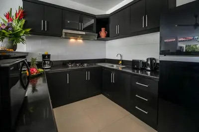a black kitchen with black cabinets and a sink at Villa Maviba in Seminyak