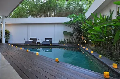 a swimming pool with chairs and a wooden deck at Villa La Sirena by Nagisa Bali in Seminyak