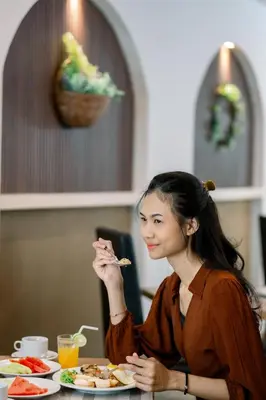 a woman sitting at a table eating food at Everyday Hotel Kuta Central in Kuta