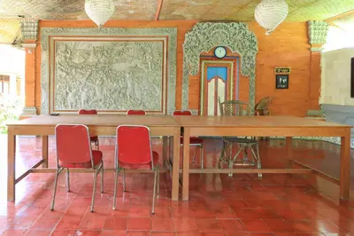 a large wooden table with red chairs in a room at Mertha Jati Hotel in Kuta
