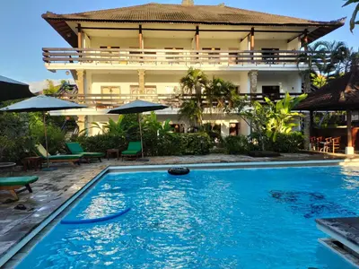 a swimming pool in front of a house at Grand Kumala Hotel - Hotel Kumala Legian Kuta Bali in Legian