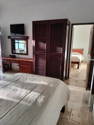 a bedroom with a bed and a dresser and a television at Grand Kumala Hotel - Hotel Kumala Legian Kuta Bali in Legian