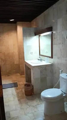 a bathroom with a toilet and a sink and a mirror at Grand Kumala Hotel - Hotel Kumala Legian Kuta Bali in Legian