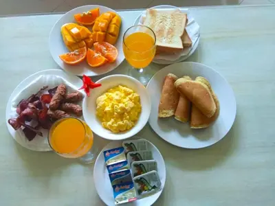 a table with plates of breakfast foods and orange juice at Kuta Regency B10 One Bedroom Villa in Kuta
