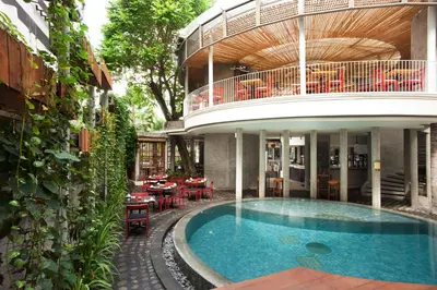 a house with a swimming pool in front of a building at Grandmas Plus Hotel Seminyak in Seminyak