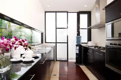a kitchen with black cabinets and a counter with pink flowers at Temple Hill Residence Villa in Jimbaran