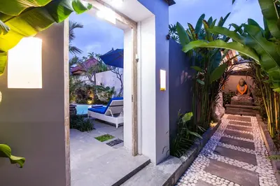 a pathway leading to a house with blue walls and plants at Ambermoon Villa 2 in Seminyak