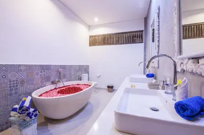 a bathroom with a large white tub next to a sink at Ambermoon Villa 2 in Seminyak