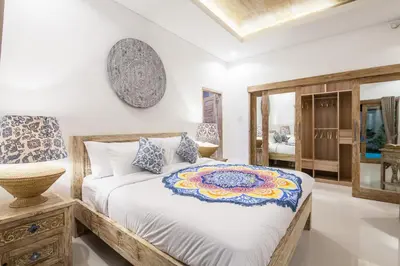 a bedroom with a large bed and a mirror at Ambermoon Villa 2 in Seminyak