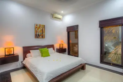 a bedroom with a bed with green pillows and two lamps at Kedis Bali Villa in Kuta