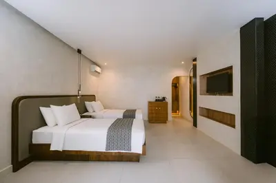 a bedroom with a white bed and a television at Legong Keraton Beach Hotel in Canggu