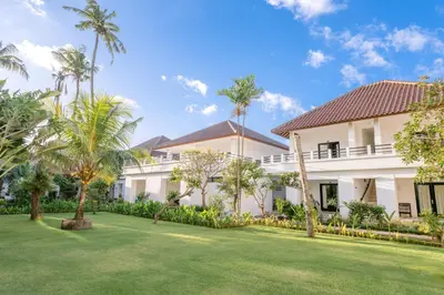 an exterior view of a villa with palm trees at Legong Keraton Beach Hotel in Canggu