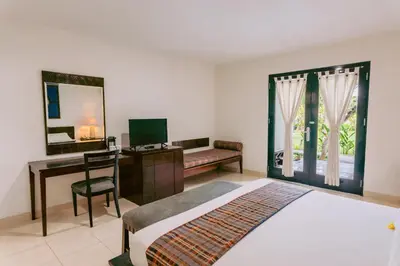 a bedroom with a bed and a desk and a computer at Legong Keraton Beach Hotel in Canggu