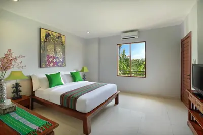 a bedroom with a large bed and a television at Villa Mawar Legian in Legian
