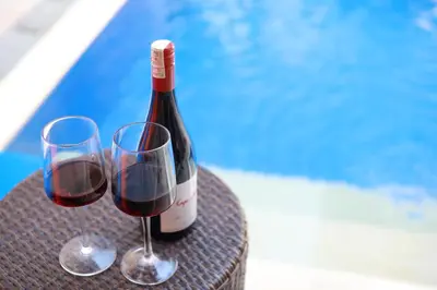 a bottle of wine and two glasses on a table at Villa Mawar Legian in Legian