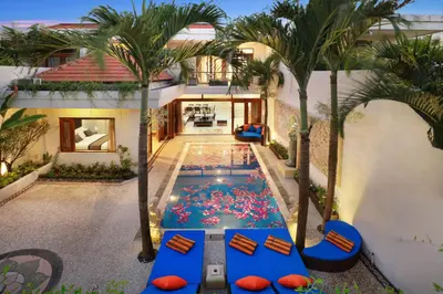 an indoor pool in the middle of a house with palm trees at Villa Mawar Legian in Legian