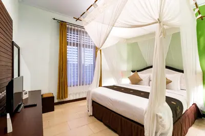 a bedroom with a canopy bed and a television at Villa Chandraika - 3BR Private Pool Villa by AGATA in Seminyak