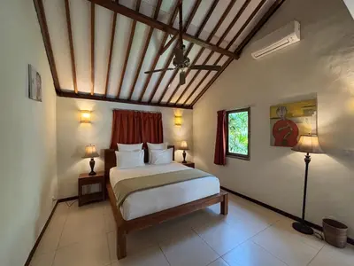 a bedroom with a bed and two lamps and a ceiling at Villa Coconut Bali in Seminyak