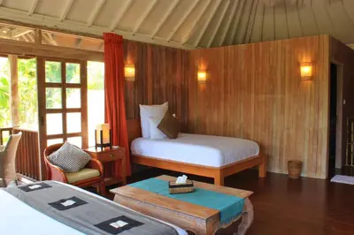 a bedroom with two beds and a table in a room at Villa Coconut Bali in Seminyak
