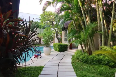 a walkway with palm trees and a swimming pool at Villa Coconut Bali in Seminyak