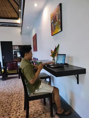 a man sitting at a desk with a laptop computer at Villa Cantik Tresna in Seminyak