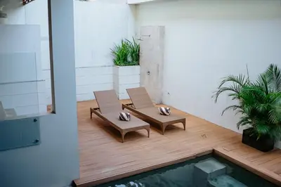two chairs and a table in a room with a pool at Villa Kayu Raja in Seminyak
