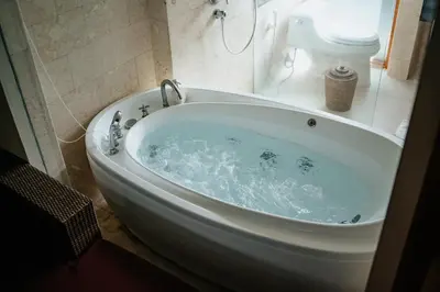 a white bath tub in a bathroom with a toilet at Villa Kayu Raja in Seminyak