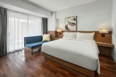 a bedroom with a large white bed and a blue couch at Fairfield by Marriott Bali Kuta Ngurah Rai in Kuta