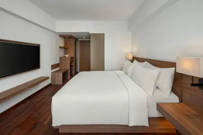 a bedroom with a white bed and a flat screen tv at Fairfield by Marriott Bali Kuta Ngurah Rai in Kuta