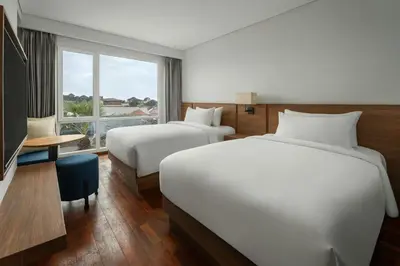 two beds in a hotel room with a window at Fairfield by Marriott Bali Kuta Ngurah Rai in Kuta