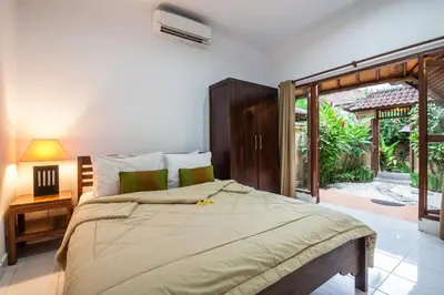 a bedroom with a large bed and a sliding glass door at Surya Mas Villa in Legian