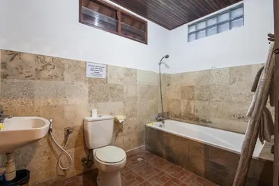 a bathroom with a toilet and a sink and a tub at Surya Mas Villa in Legian