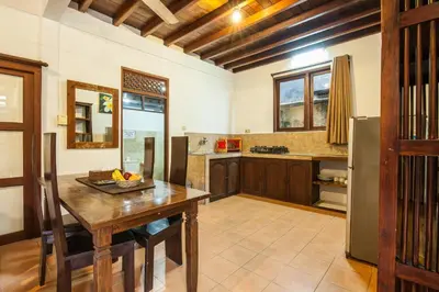 a kitchen with a wooden table and a refrigerator at Surya Mas Villa in Legian