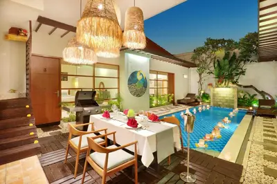 a dining room with a table and a swimming pool at The Vie Villa Legian in Legian