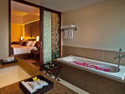a bathroom with a bath tub and a bedroom at Sun Island Hotel & Spa Kuta in Kuta