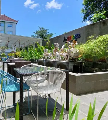 a table and chairs and a fountain in a garden at Zuri Express Jimbaran in Jimbaran