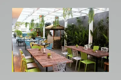 a restaurant with wooden tables and chairs and plants at Zuri Express Jimbaran in Jimbaran
